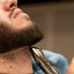 Barbeiro ajustando a barba masculina em estilo tendência 2025