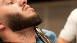 Barbeiro ajustando a barba masculina em estilo tendência 2025