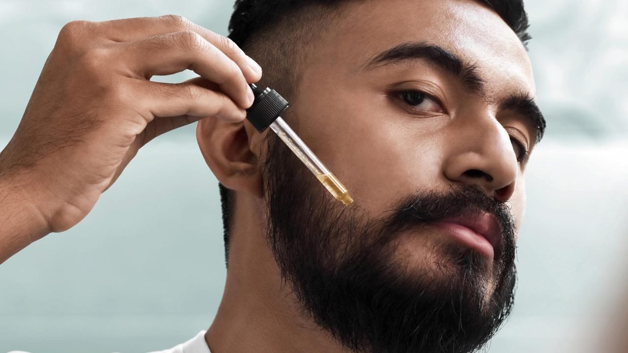 homem aplicando óleo para barba para hidratar e evitar frizz