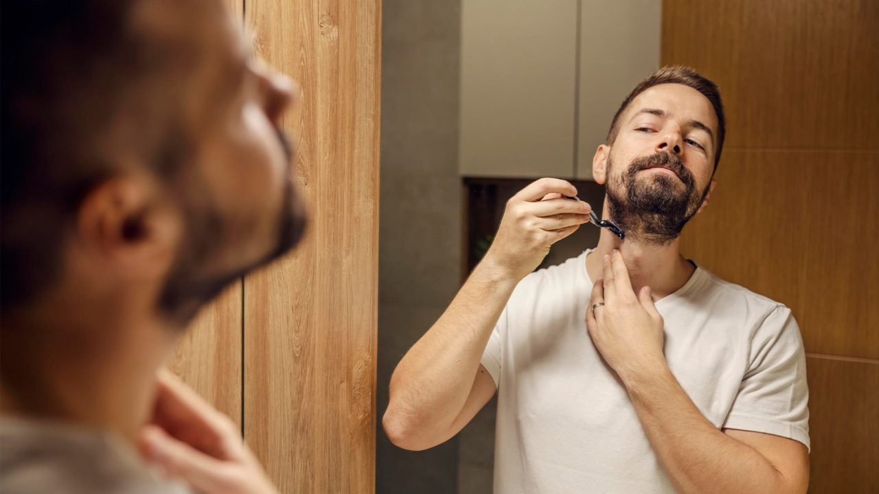 homem fazendo rotina de cuidados com a barba usando pente e produtos
